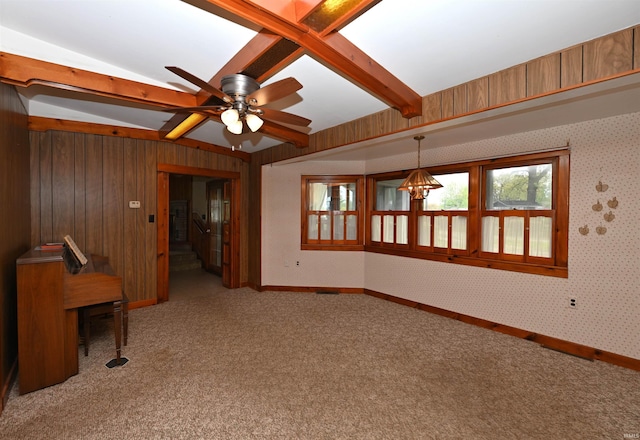 spare room featuring carpet floors, a ceiling fan, baseboards, and wood walls