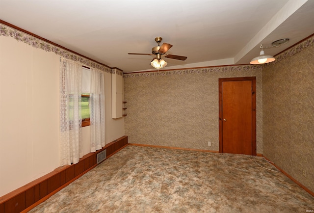 carpeted empty room with a ceiling fan and wallpapered walls
