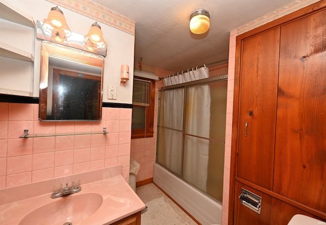 full bath with combined bath / shower with glass door, tile walls, and vanity