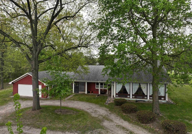 view of front facade with dirt driveway, a garage, roof with shingles, and a front yard