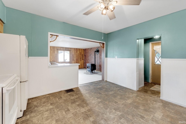 3648 E 300 S, Albion, IN 46701 - empty room with a wood stove, wainscoting, a ceiling fan, and wood walls