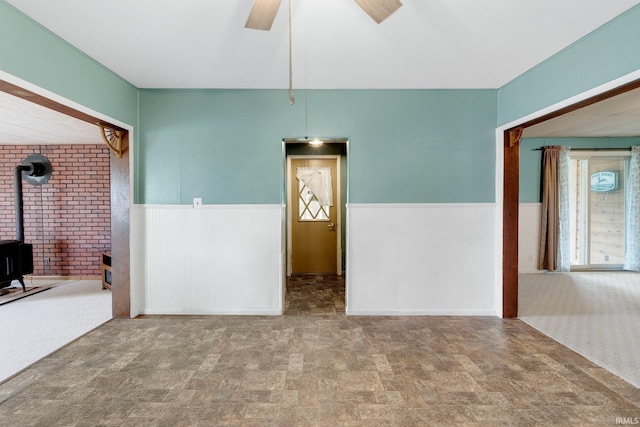 3648 E 300 S, Albion, IN 46701 - unfurnished room with a wood stove, a wainscoted wall, and a ceiling fan