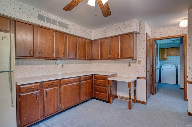 844 Old Plank Rd, Chandler, IN 47610 - kitchen with washer / clothes dryer, wallpapered walls, freestanding refrigerator, brown cabinets, and ceiling fan