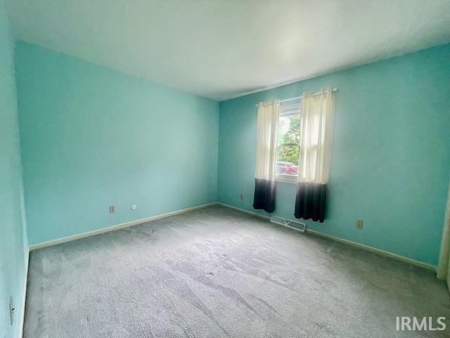 carpeted spare room featuring baseboards