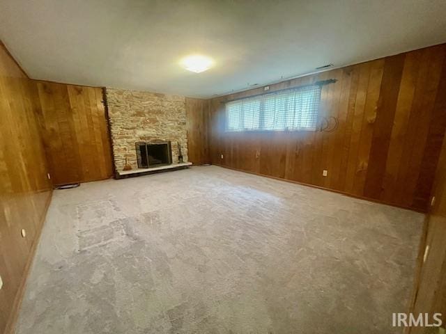 unfurnished living room featuring wooden walls, carpet flooring, and a fireplace