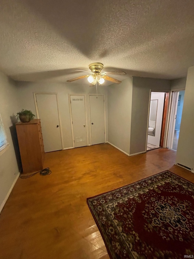 109 S 3rd St, Edwardsport, IN 47528 - unfurnished bedroom featuring a textured ceiling, baseboards, light wood finished floors, a ceiling fan, and ensuite bath