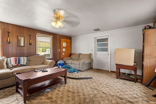 living room with a ceiling fan, carpet flooring, and wooden walls