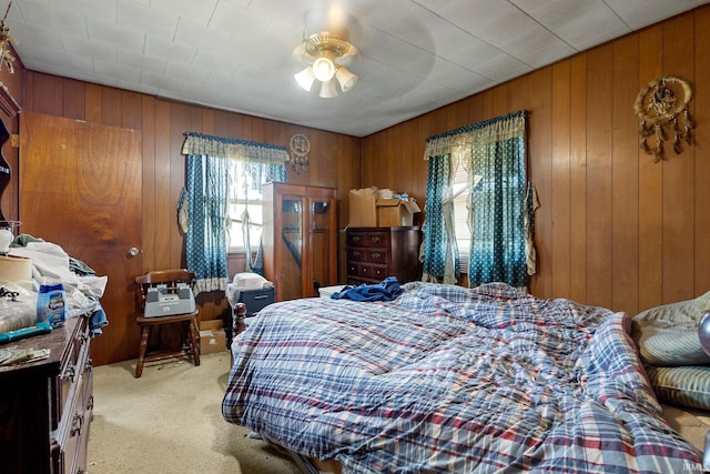 bedroom with light carpet and wooden walls
