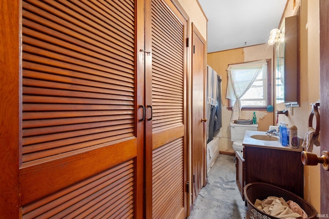 bathroom with toilet, vanity, tub / shower combination, and concrete floors