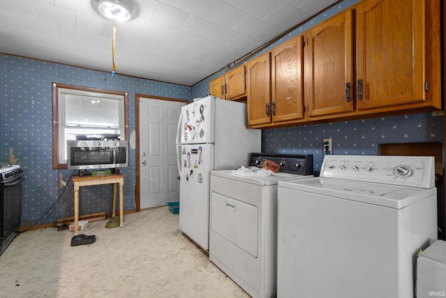 laundry area featuring wallpapered walls, washer and dryer, and light flooring