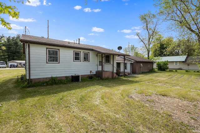 back of property featuring a lawn and central air condition unit