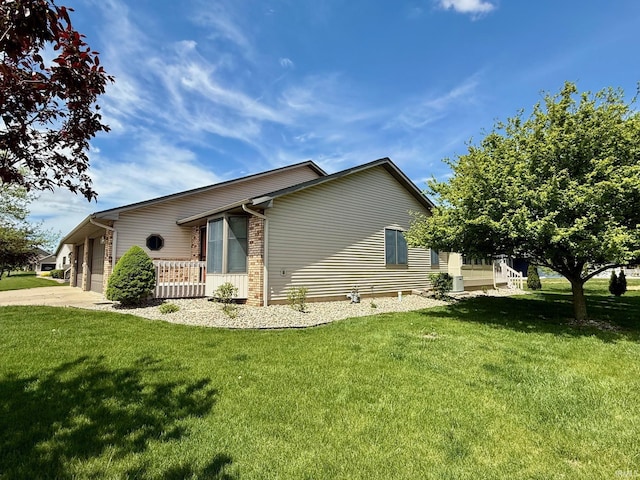 view of side of property with concrete driveway, a garage, a yard, and brick siding