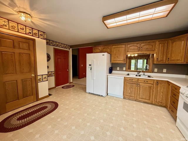kitchen with white appliances, a sink, light countertops, brown cabinetry, and light floors