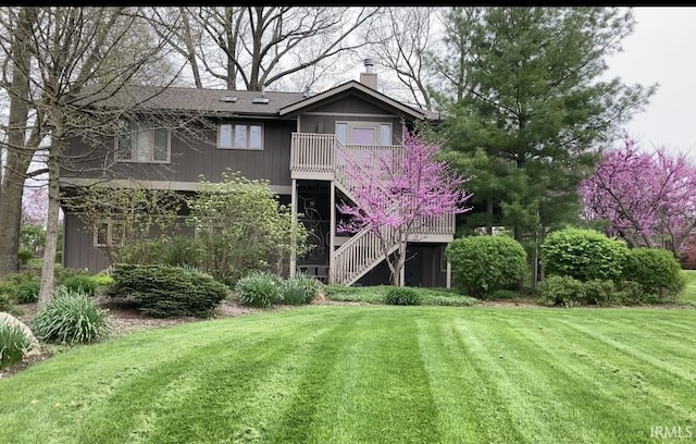 back of property featuring a lawn, a chimney, and stairs