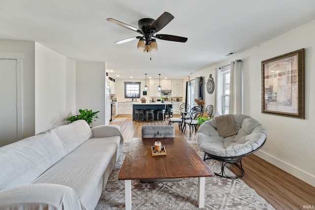 1308 Tedlee Dr, Kokomo, IN 46901 - living room featuring light wood-style flooring, baseboards, a ceiling fan, and healthy amount of natural light
