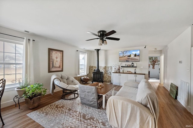 1308 Tedlee Dr, Kokomo, IN 46901 - living area featuring a wood stove, wood finished floors, plenty of natural light, and a ceiling fan