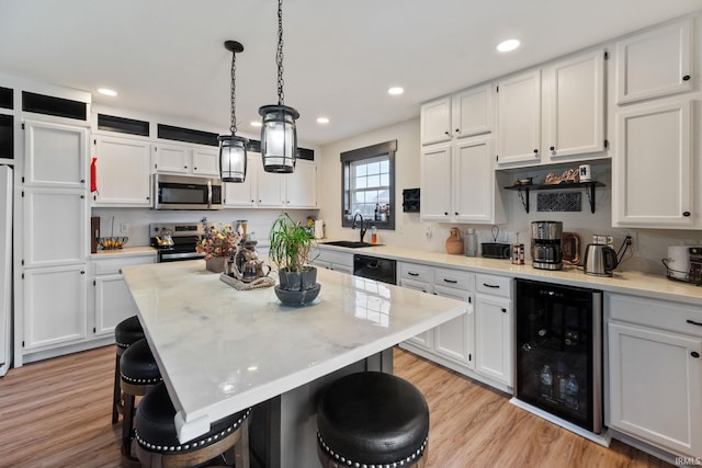 1308 Tedlee Dr, Kokomo, IN 46901 - kitchen with beverage cooler, appliances with stainless steel finishes, a breakfast bar, white cabinets, and a sink