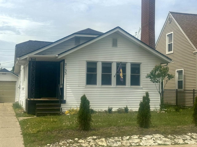 view of side of home with a chimney, an outdoor structure, and driveway