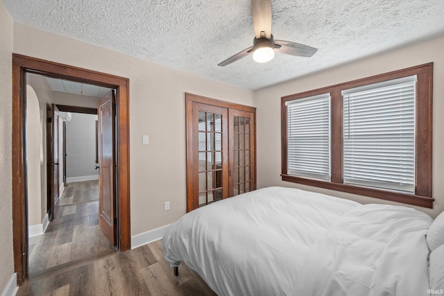 bedroom with wood finished floors, a closet, baseboards, a ceiling fan, and a textured ceiling