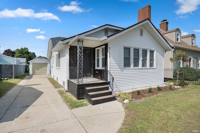view of front of house with an outbuilding, driveway, a garage, and a chimney