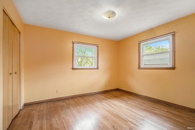 56226 Tanglewood Ln, Osceola, IN 46561 - unfurnished bedroom featuring multiple windows, light wood-style flooring, a closet, and baseboards