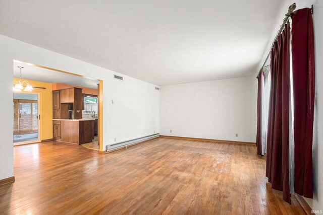 56226 Tanglewood Ln, Osceola, IN 46561 - unfurnished living room with a baseboard heating unit, light wood finished floors, a chandelier, and baseboards