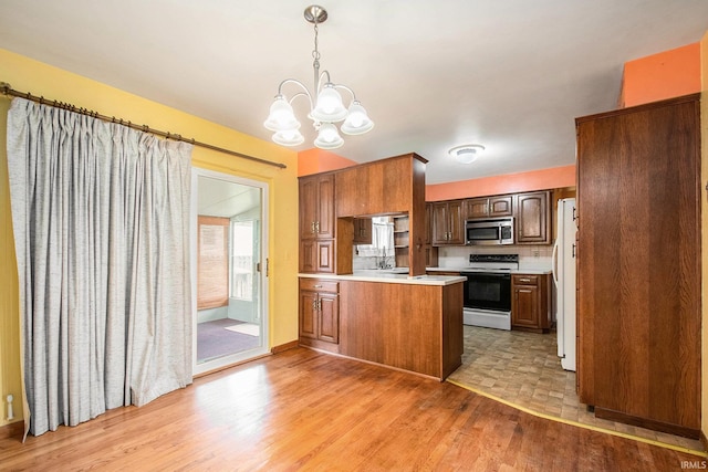56226 Tanglewood Ln, Osceola, IN 46561 - kitchen featuring range with electric cooktop, stainless steel microwave, a peninsula, light wood-style floors, and light countertops