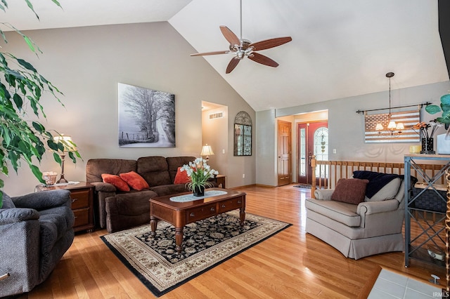living room with high vaulted ceiling, a ceiling fan, light wood-style flooring, and a chandelier
