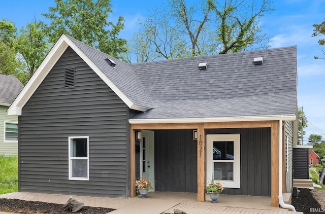 back of house with roof with shingles and board and batten siding