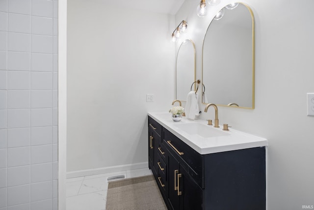 bathroom featuring double vanity, marble finish floors, and baseboards