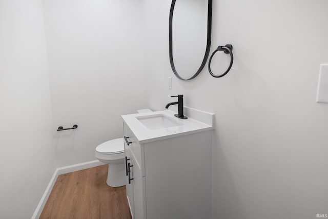 bathroom featuring vanity, wood finished floors, toilet, and baseboards