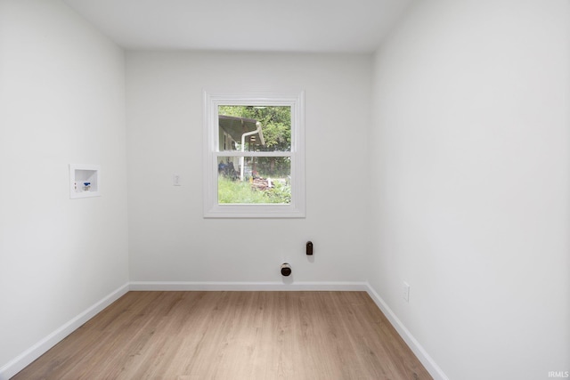 clothes washing area with washer hookup, light wood-style floors, and baseboards