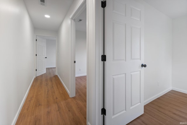 hallway featuring wood finished floors, baseboards, and recessed lighting