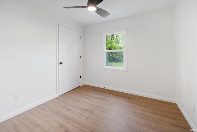 spare room with light wood-style floors, a ceiling fan, and baseboards
