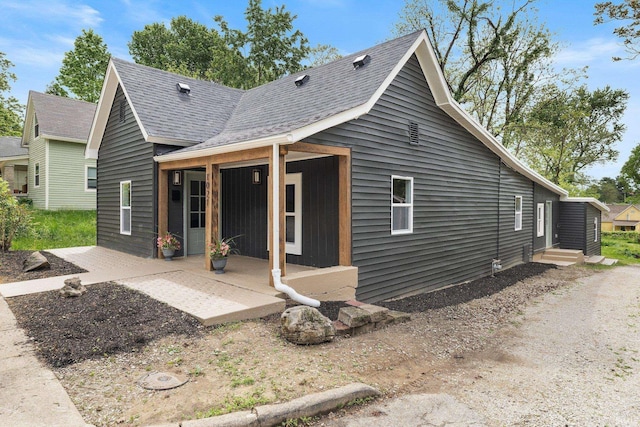 rear view of property with a shingled roof and a patio area