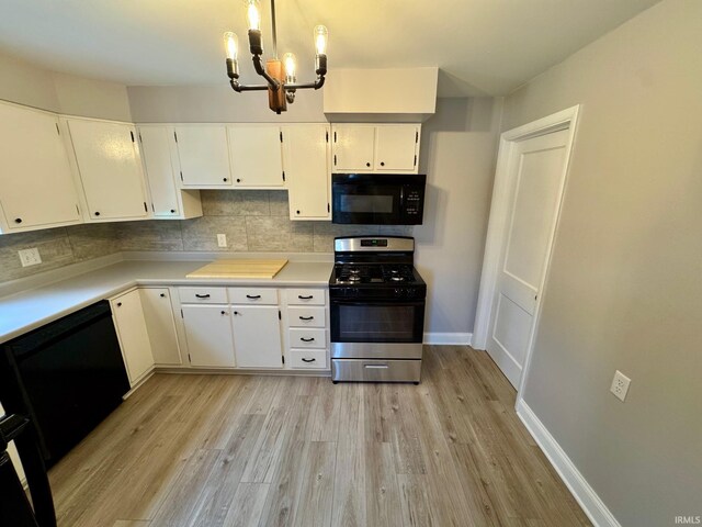 kitchen featuring black microwave, gas stove, a chandelier, and light wood-style flooring