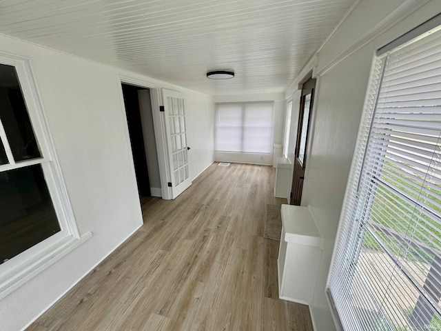 corridor with light wood-style flooring and baseboards