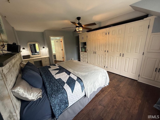 bedroom with dark wood-style floors, a ceiling fan, and multiple closets