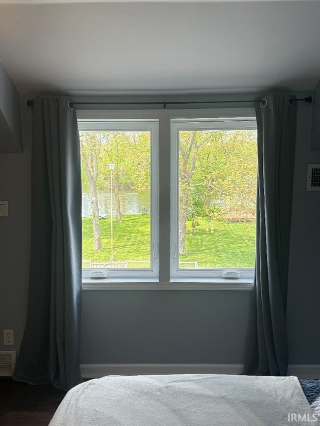 bedroom with a water view and baseboards