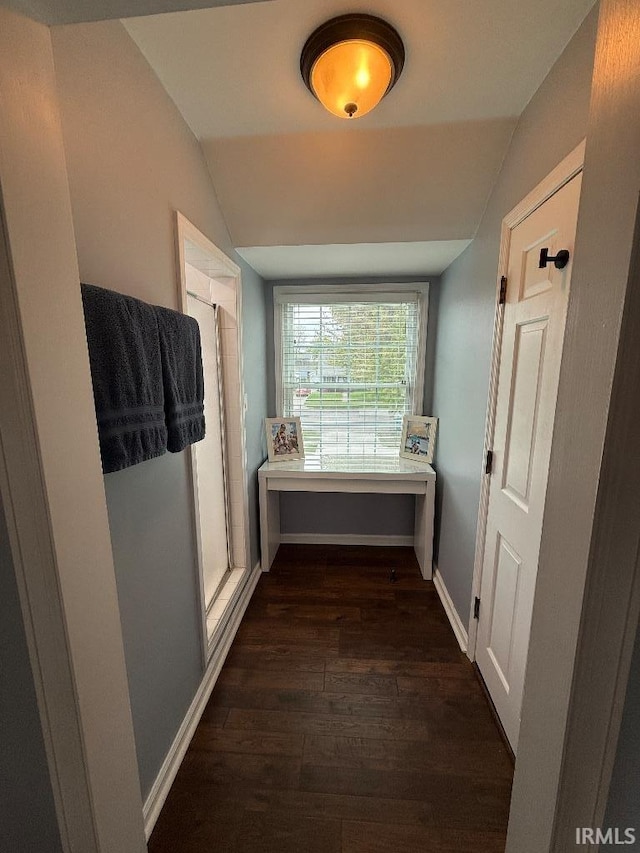corridor featuring lofted ceiling, dark wood-style flooring, and baseboards