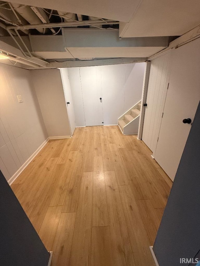 finished below grade area featuring light wood finished floors and stairway