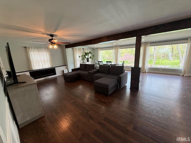 living room with dark wood-type flooring, a ceiling fan, and a fireplace