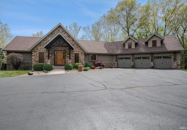 51205 County Road 25th Rd, Bristol, IN 46507 - view of front of house featuring stone siding, asphalt driveway, a garage, and roof with shingles