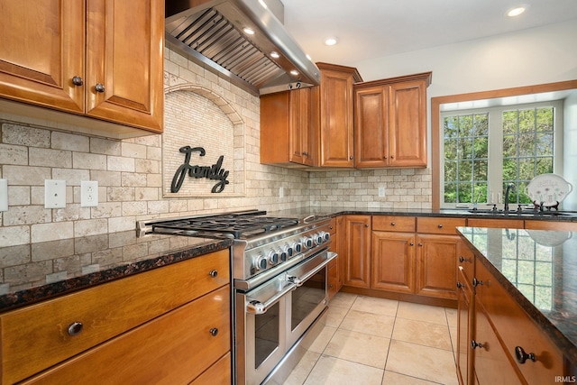 51205 County Road 25th Rd, Bristol, IN 46507 - kitchen with range with two ovens, ventilation hood, brown cabinets, backsplash, and dark stone counters