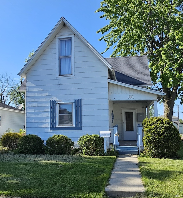 view of front of property featuring a front lawn and a shingled roof