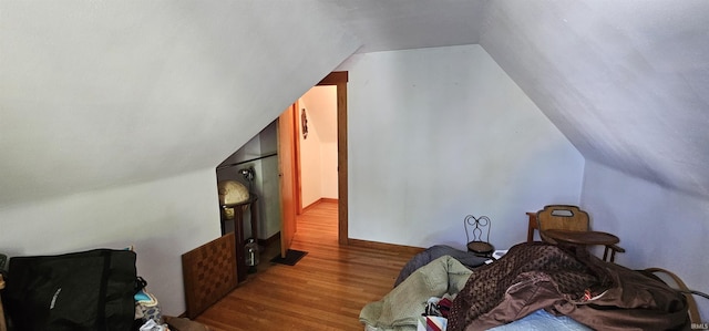 additional living space with wood finished floors and vaulted ceiling