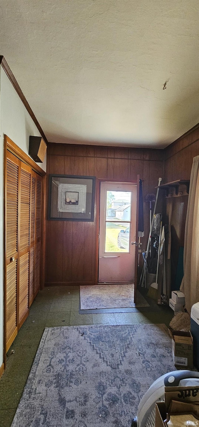 entrance foyer featuring wood walls, crown molding, and a textured ceiling