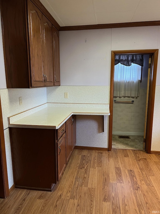 unfurnished office featuring light wood-style flooring, ornamental molding, and baseboards