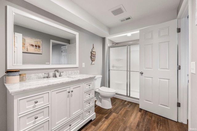 bathroom featuring toilet, a stall shower, wood finished floors, and vanity