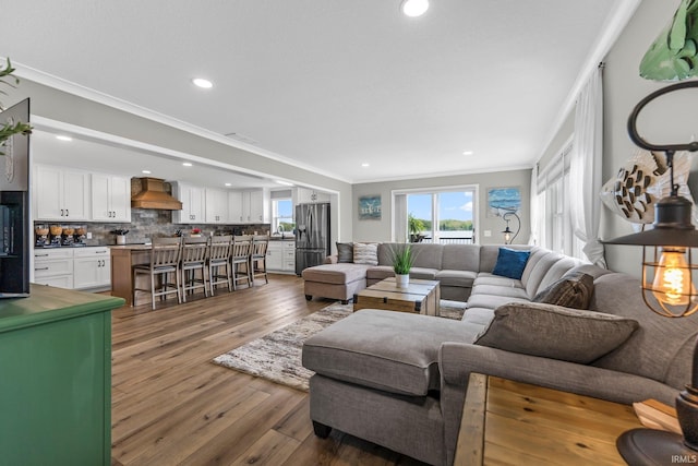 living area featuring crown molding, wood finished floors, and recessed lighting